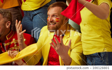 Close-up of bearded man. People, football, soccer fans emotionally watching match, cheering up favourite team. Fans wearing colorful scarves and flags Close-up of bearded man. People, football, soccer fans emotionally watching match, cheering up favourite team. Fans wearing colorful scarves and flags 100128801