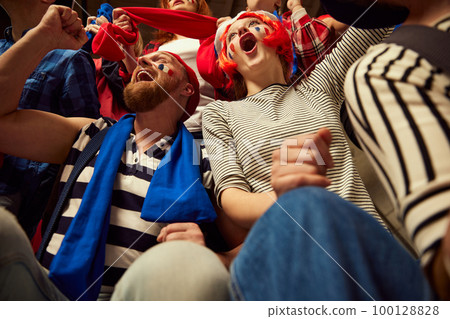 Bottom view. Football, soccer fans emotionally cheering up favourite france team. People wearing colorful scarfs at crowded stadium Bottom view. Football, soccer fans emotionally cheering up favourite france team. People wearing colorful scarfs at crowded stadium 100128828