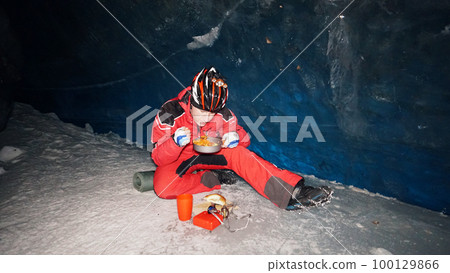 A mountaineer caver eats in a deep ice cave A mountaineer caver eats in a deep ice cave 100129866