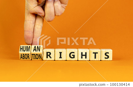 Abortion rights symbol. Concept words Abortion rights are human rights on wooden cubes. Businessman hand. Beautiful orange table orange background. Business medical abortion rights concept. Copy space 100130414