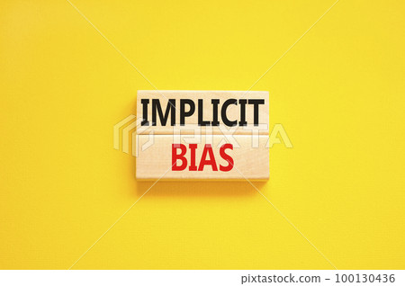 Implicit bias symbol. Concept words Implicit bias on wooden block. Beautiful yellow table yellow background. Business psychology implicit bias concept. Copy space. 100130436