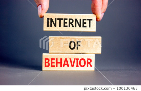 Internet of behavior symbol. Concept words Internet of behavior on wooden block on a beautiful grey table grey background. Businessman hand. Business Internet of behavior concept. Copy space. 100130465