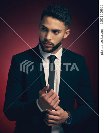 Dress for the job you want. Studio shot of a young man posing against a red background. 100130992
