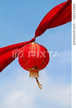 Red Chinese lantern in the air decorating the streets of China. Traditional Asian decor for new year celebrations in beautiful sky background. Creative cultural art hanging high up on a summer day 100131082