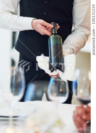 Waiter hands, wine and restaurant table with white towel, luxury hospitality and vintage for fine dining. Man, bottle service and holding drink for customer decision at celebration on valentines day Waiter hands, wine and restaurant table with white towel, luxury hospitality and vintage for fine dining. Man, bottle service and holding drink for customer decision at celebration on valentines day 100131224