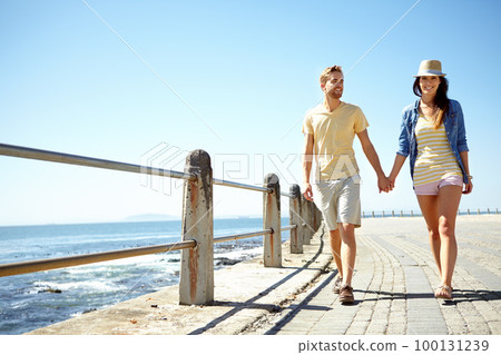 Beach, travel and happy couple holding hands while walking, talking and having fun on summer vacation. Sea, holiday and young man with woman bond, calm and happy, smile and relax together in Florida Beach, travel and happy couple holding hands while walking, talking and having fun on summer vacation. Sea, holiday and young man with woman bond, calm and happy, smile and relax together in Florida 100131239