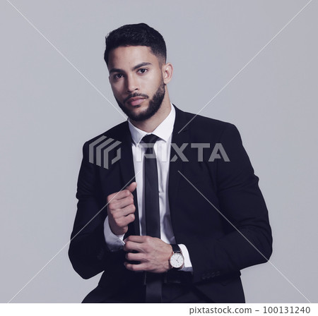 Hes all about business. Studio shot of a young man posing against a grey background. Hes all about business. Studio shot of a young man posing against a grey background. 100131240