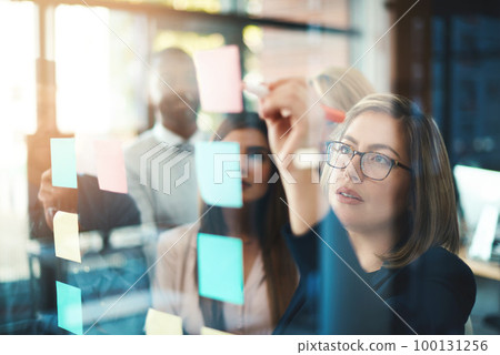 Marketing leader planning and writing on sticky notes on wall while support and sharing vision or idea. Diverse group of creative office business people meeting together to market new startup company 100131256