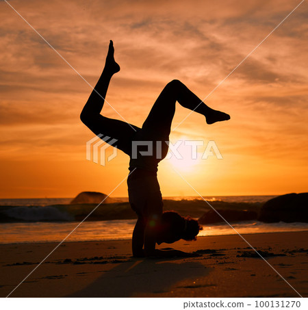Yoga, silhouette or handstand on sunset beach, ocean or sea in evening workout or relax exercise training. Yogi, woman or sand balance pose at sunrise for healthcare wellness fitness or strong body 100131270