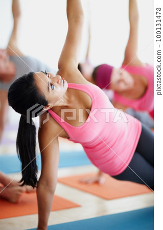 Reaching new heights in health. A pretty young woman stretching towards the ceiling during a yoga class. Reaching new heights in health. A pretty young woman stretching towards the ceiling during a yoga class. 100131478