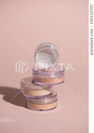 Mineral powder of beige and tan colors on pale rose colour background with shadows - beauty and make up concept Mineral powder of beige and tan colors on pale rose colour background with shadows - beauty and make up concept 100132505