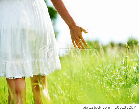 Touching nature. Cropped view of a young woman walking through a green field. Touching nature. Cropped view of a young woman walking through a green field. 100133297