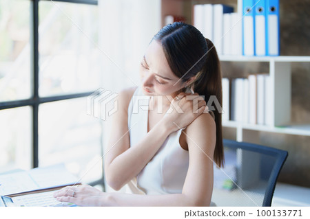 Portrait of young Asian female representative showing shoulder pain from sitting for a long time. 100133771