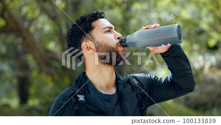 Man drinking water hiking in a forest, nature or woods outdoors in jungle adventure with freedom in Costa Rica. Healthy, fitness and thirsty hiker trekking or walking on a journey refreshing on break 100133839