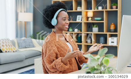 Call center agent talking and helping customers while wearing a headset and working on a desktop computer at home. Happy and cheerful black woman working in sales and networking with clients online 100134029