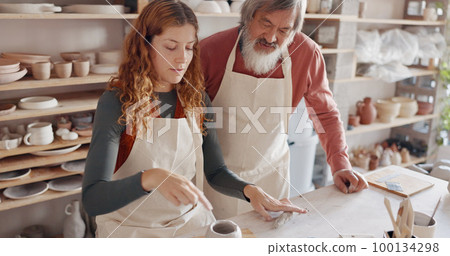 Art teacher, pottery and senior man in a class, learning tips in art class. Young woman teaching old man to roll clay, sculpture and giving instruction in studio to learn new skill in retirement 100134298