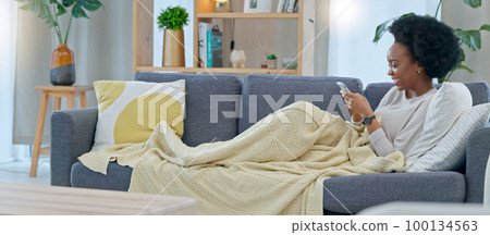 Happy black woman reading social media gossip on phone while relaxing on a sofa at home. Young African American female texting and sharing an interesting scandal, shocked about drama on the internet Happy black woman reading social media gossip on phone while relaxing on a sofa at home. Young African American female texting and sharing an interesting scandal, shocked about drama on the internet 100134563
