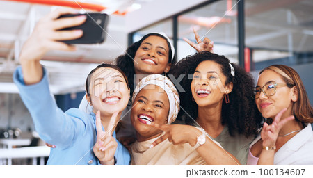 Business people, peace sign and phone selfie in office for happy memory, profile picture or social media. Tech, cellphone and group of women, friends or coworkers taking pictures on mobile smartphone 100134607