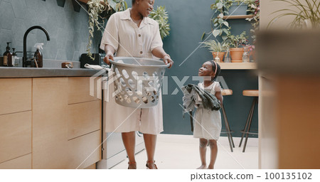 Laundry, mother and child helping with folding of clothes together in a house. Happy, excited and young girl giving help to her mom while cleaning clothing from a washing machine in their home Laundry, mother and child helping with folding of clothes together in a house. Happy, excited and young girl giving help to her mom while cleaning clothing from a washing machine in their home 100135102