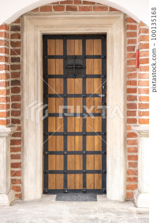 Old wooden brown house door. Gorgeous wooden door in the streets Krakow Poland. antique wooden door with wrought-iron 100135168
