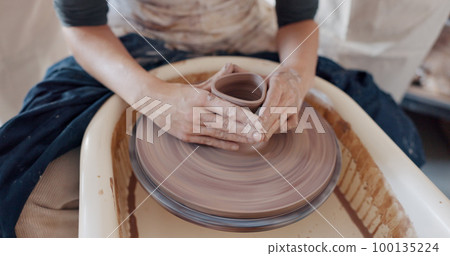 Pottery, art and hands on a potter wheel with artist spinning clay in creative class, workshop or studio. Creativity, handicraft and closeup of a sculptor working on ceramic design, craft or creation Pottery, art and hands on a potter wheel with artist spinning clay in creative class, workshop or studio. Creativity, handicraft and closeup of a sculptor working on ceramic design, craft or creation 100135224