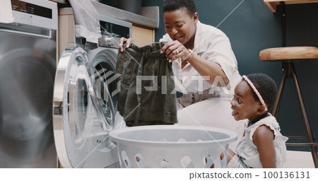 Laundry, mother and child helping with folding of clothes together in a house. Happy, excited and young girl giving help to her mom while cleaning clothing from a washing machine in their home Laundry, mother and child helping with folding of clothes together in a house. Happy, excited and young girl giving help to her mom while cleaning clothing from a washing machine in their home 100136131
