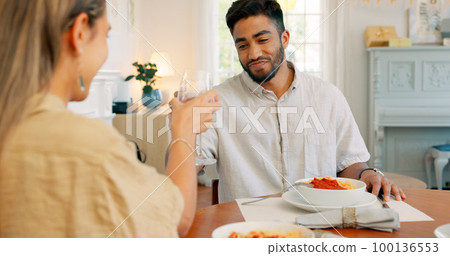 Toast, love and couple on a wine date in a house in celebration of a happy marriage and anniversary. Smile, romance and young woman drinking alcohol and eating spaghetti food with a romantic partner 100136553