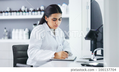 Young scientist using a computer and microscope in a lab. Female pathologist analyzing medical samples while doing experiments to develop a cure. Microbiologist conducting forensic research Young scientist using a computer and microscope in a lab. Female pathologist analyzing medical samples while doing experiments to develop a cure. Microbiologist conducting forensic research 100137704