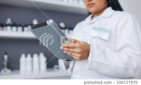 Young scientist using a digital tablet and microscope in a lab. Female pathologist analyzing medical samples while doing experiments to develop a cure. Microbiologist conducting forensic research Young scientist using a digital tablet and microscope in a lab. Female pathologist analyzing medical samples while doing experiments to develop a cure. Microbiologist conducting forensic research 100137876