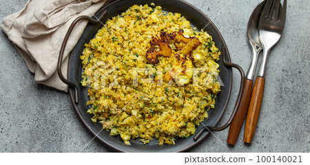 Fried cauliflower rice or couscous with dill on plate, healthy low carbohydrates vegetable side dish for keto diet and healthy low calories nutrition, rustic stone background 100140021