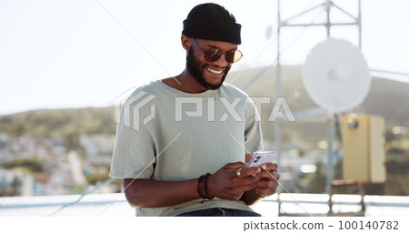 Phone, texting and happy black man on rooftop of city building using smartphone for social media, chatting and communication. Fashion, meme and young trendy guy typing message, text or post in town Phone, texting and happy black man on rooftop of city building using smartphone for social media, chatting and communication. Fashion, meme and young trendy guy typing message, text or post in town 100140782
