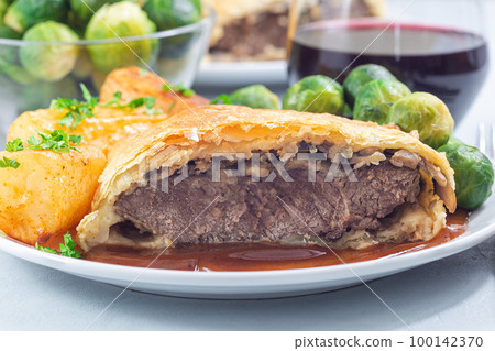 Beef Wellington with mushroom Duxelles, served with brussels sprouts and Chateau potato, closeup 100142370