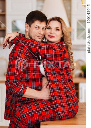 a pregnant woman and a man in pajamas in the kitchen 100143045