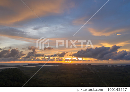 aerial view beautiful yellow sunrise above the mountain in phang Nga valley. slow floating fog blowing cover on the mountain look like as a sea of mist. scenery golden sunrise at horizon background. aerial view beautiful yellow sunrise above the mountain in phang Nga valley. slow floating fog blowing cover on the mountain look like as a sea of mist. scenery golden sunrise at horizon background. 100143237