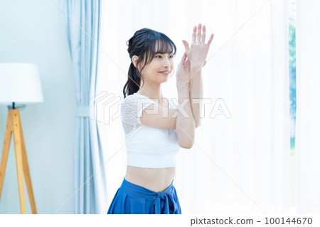Young woman doing yoga in a bright living room 100144670