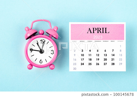 The April 2023 Monthly calendar year with pink alarm clock on blue colour background. The April 2023 Monthly calendar year with pink alarm clock on blue colour background. 100145678