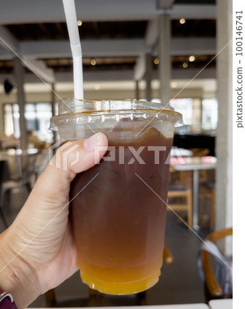Hand holding glass of iced americano 100146741