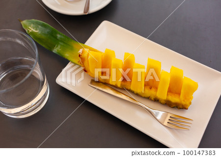 Pineapple chunks on white plate on gray background 100147383