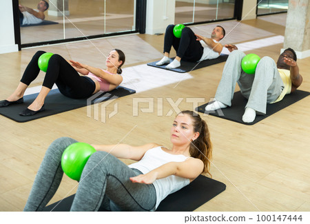 Sporty young adults doing pilates exercises with bender balls Sporty young adults doing pilates exercises with bender balls 100147444