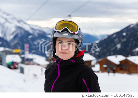 Woman in ski helmet and goggles spending winter holidays in ski resort 100147583