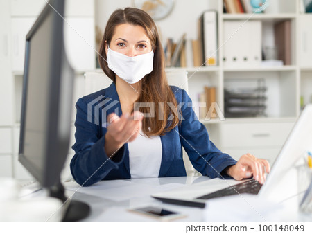 Business woman in face mask holding meeting in office 100148049