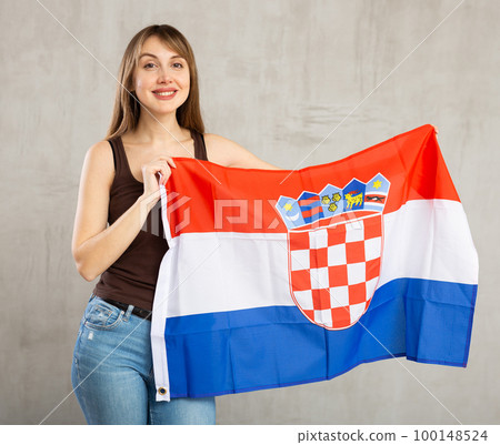 Happy young woman holding flag of Croatia against unicoloured background Happy young woman holding flag of Croatia against unicoloured background 100148524