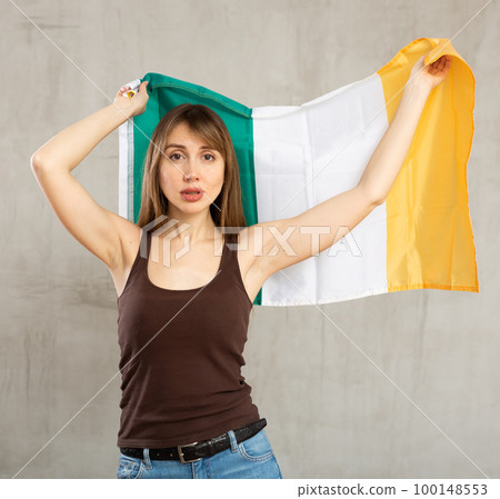 Upset woman standing with flag of Ireland on gray background Upset woman standing with flag of Ireland on gray background 100148553