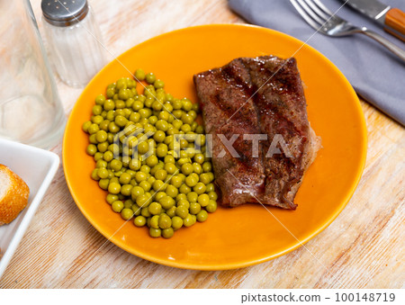 Fried beef cutlet with green peas on plate Fried beef cutlet with green peas on plate 100148719