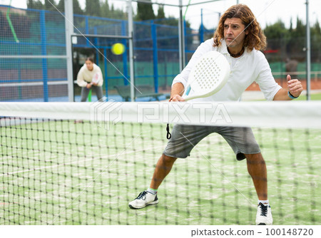 Caucasian man playing paddle tennis on padel court 100148720