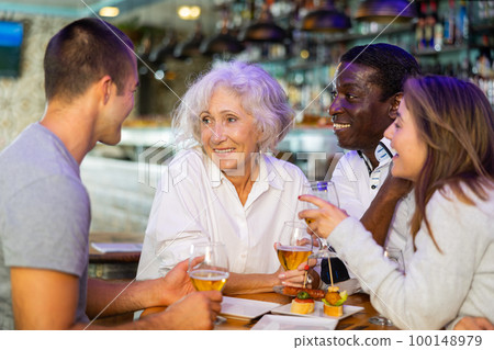 Spending time in bar. Four positive friends drinking beer 100148979