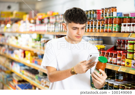 Young male customer scanning qr-code on jar of preserved food 100149069
