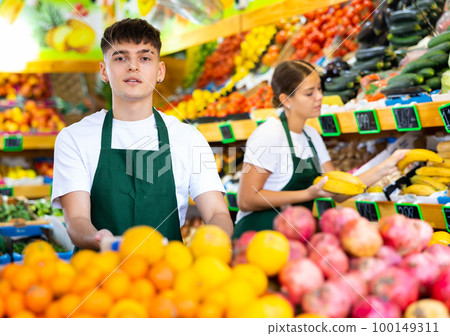 Portrait of friendly young male supermarket worker in fruit section 100149311