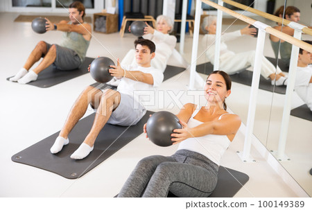 Young woman practicing pilates with ball in gym room 100149389