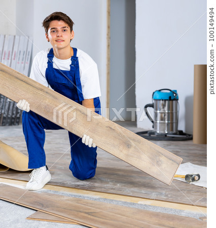 Professional male builder laying laminate flooring in room being renovated Professional male builder laying laminate flooring in room being renovated 100149494